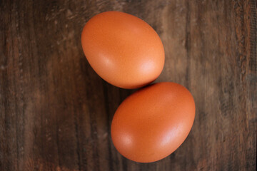 Close-up view of raw chicken eggs in egg basket on brown wooden background