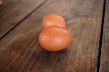 Close-up view of raw chicken eggs in egg basket on brown wooden background