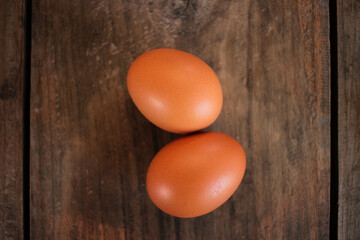 Close-up view of raw chicken eggs in egg basket on brown wooden background