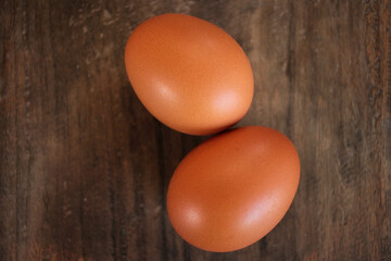 Close-up view of raw chicken eggs in egg basket on brown wooden background