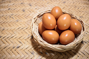 Close-up view of raw chicken eggs in egg basket on brown wooden background