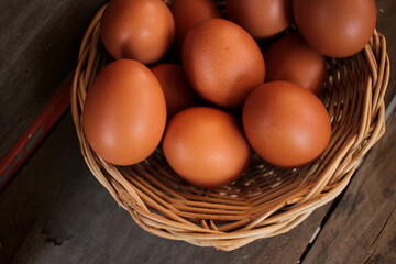 Close-up view of raw chicken eggs in egg basket on brown wooden background