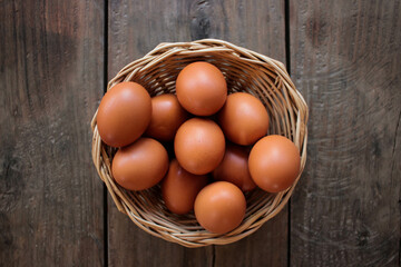 Close-up view of raw chicken eggs in egg basket on brown wooden background
