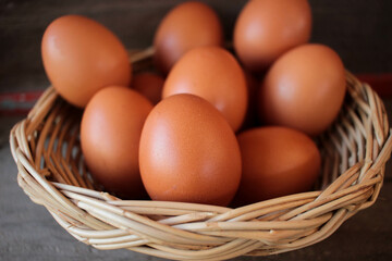 Close-up view of raw chicken eggs in egg basket on brown wooden background