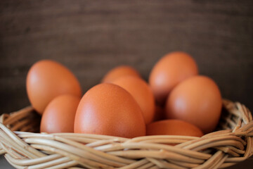 Close-up view of raw chicken eggs in egg basket on brown wooden background