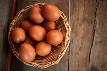 Close-up view of raw chicken eggs in egg basket on brown wooden background