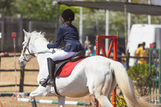 Equestrian sport - a teenage girl in uniform riding a horse at the ranch