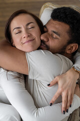 Multiethnic couple embracing at home.