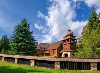Fototapeta na wymiar Wooden evangelical articular church of the Svaty Kriz(Holy Cross), is one of the largest wooden churches in Europe.Green meadow, flowering dandelion, old architecture. Paludza, Svaty Kriz, 