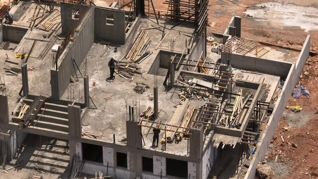 Aerial view on workers at a construction site for building a new house, 4k drone footage