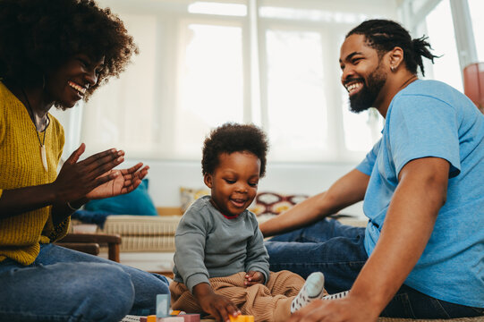 A happy little african american boy is solving a educational game while his parents are clapping and encouraging him.