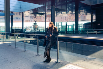 Young Latin woman tourist in warn clothes looking out with professional photo camera in Reina Sofia...