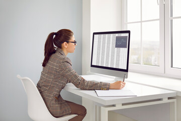 Serious busy young woman in suit working on office computer. Professional financial accountant or...