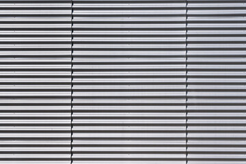 Wall made of strips of gray aluminum profile. Horisontal lines...