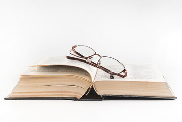 On a white background, an open bible and glasses. Religion concept.