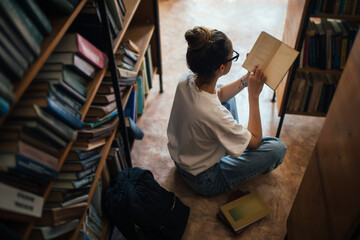 A student stuying and reading books in a public library. © polinaloves