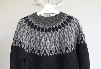 Icelandic wool knitted lopapeysa sweater, dark grey black pullover with large yoke in traditional Nordic knitting pattern close up
