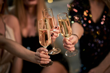Female Friends Make Toast As They Celebrate At Party. Group of partying girls clinking flutes - obrazy, fototapety, plakaty