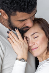 Multiethnic couple embracing at home.