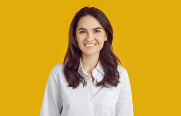 Profile picture studio headshot of business manager or company website consultant. Portrait smiling beautiful young woman in white shirt with perfect teeth isolated on bright yellow colour background