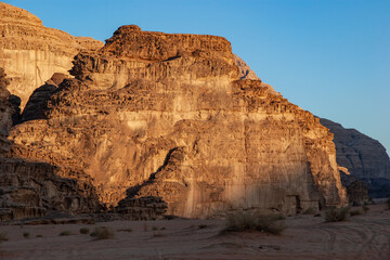 Fototapeta premium Magic mountain landscapes of Wadi Rum Desert, Jordan. Mountains in lifeless desert resemble Martian craters. Sand is beautiful pink color and and red rocks. There is place for text.