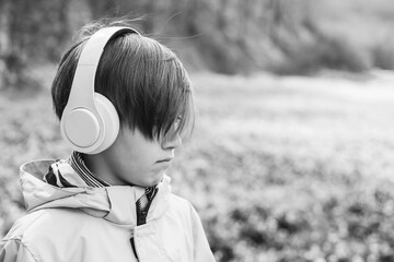 Upset boy with headphones on the walk. Lifestyle, childhood and emotions.