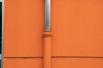 eaves or downspout, particular house of the facade on a building with orange plaster. stainless steel water drain pipes