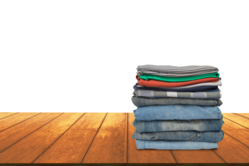 Pile of washed and neatly stored clothes on brown wooden table isolated on white background.	PNG