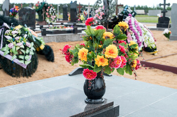 A vase with artificial flowers on the grave of the deceased.