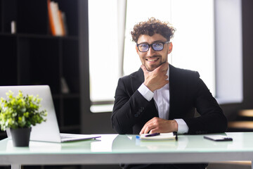 Obraz premium Businessman sitting at office desk working on laptop