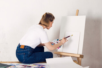 The art school student is painting on a canvas.