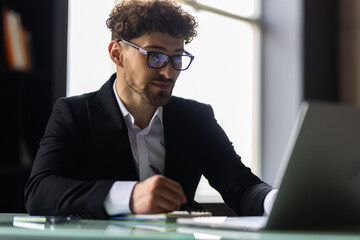 Businessman working in office. Young handsome man working on laptop.