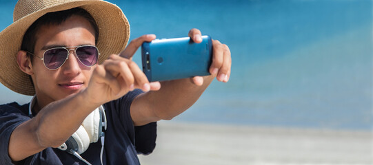 young man making a selfie with phone on the beach