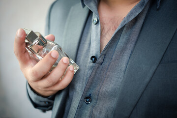 Handsome man in suit with bottle of perfume, Man applying perfume