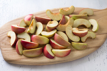 Wooden board with sliced apples for baking or other dishes on a light blue background