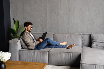 Young handsome man surfing on tablet on a couch