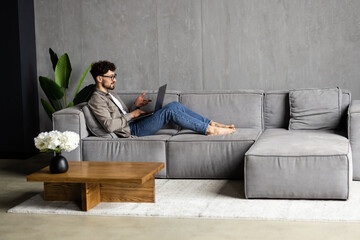 Portrait of a handsome young businessman sitting on a modern couch, holding a digital tablet