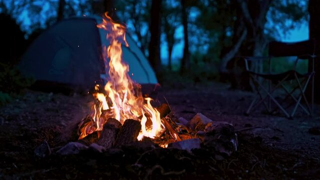 Camping fire with a tent in the background