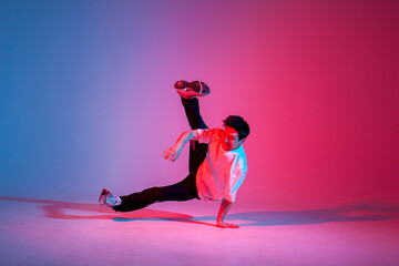 guy hiphop performer break dance in neon club lighting and doing acrobatic trick, male dancer...