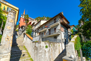 Fototapeta na wymiar View from the bottom of a long staircase looking towards the Church of San Giorgio and it's red spire in the lakefront picturesque town of Varenna, Italy at summer.