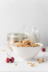 Bowl of homemade granola with nuts in white bowl on light background. Quick healthy breakfast
