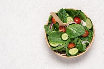Fresh green salad in cardboard bowl on white background with copy space. Healthy food delivery concept