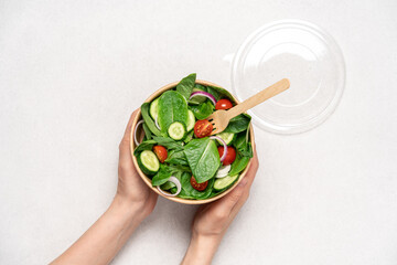 Fresh green salad in cardboard bowl on white background with copy space. Healthy food delivery...