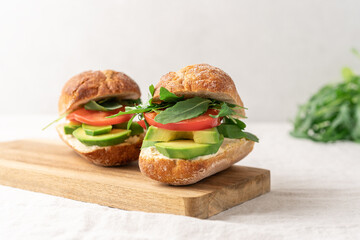Avocado sandwich with hummus and tomatoes on white background side view with copy space. Healthy snack, fast food