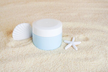 Cosmetic cream in blue bottle with Starfish on the sand background, copy space. UVA and UVB protection. Summer cosmetics