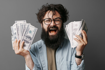 Handsome bearded man holds money in hand. Satisfied bearded man in denim shirt demonstrating bundle...