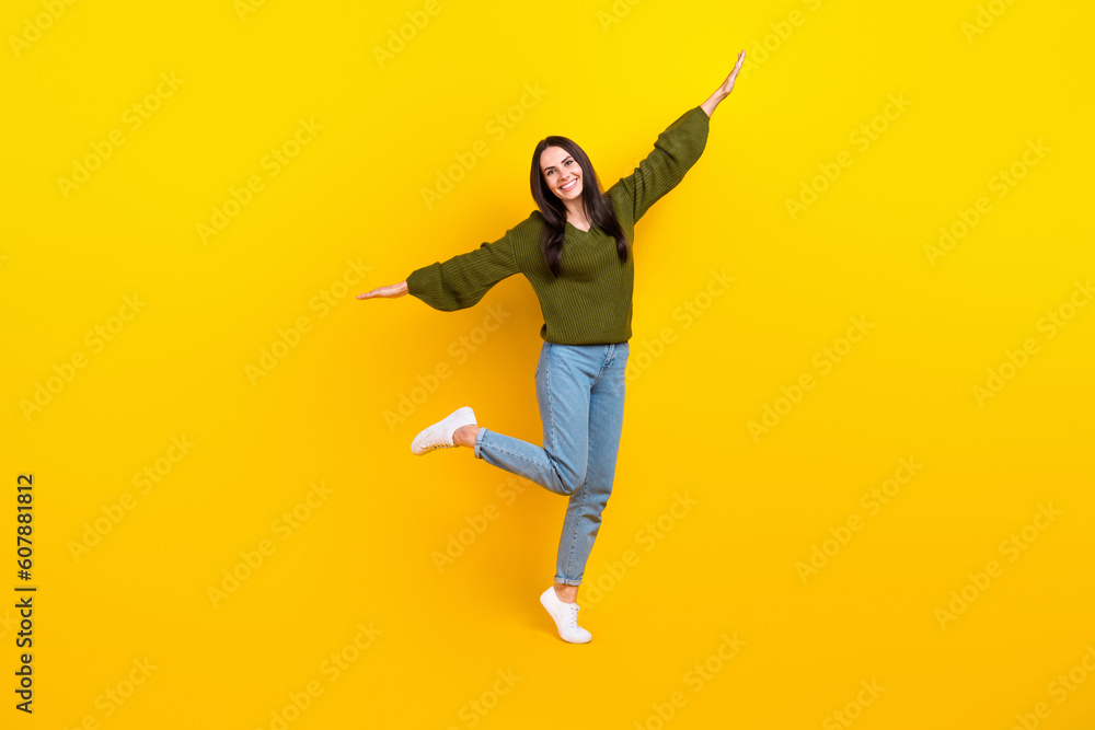 Poster Full size photo of overjoyed nice girl stand one leg arms wings good mood isolated on yellow color background