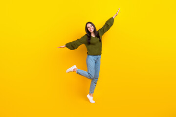 Fototapeta na wymiar Full size photo of overjoyed nice girl stand one leg arms wings good mood isolated on yellow color background