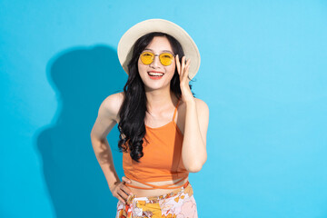 Portrait of a beautiful asian girl in a swimsuit smiling happily on a blue background - obrazy, fototapety, plakaty