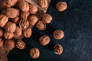 Shelled and unshelled walnuts on dark grunge background. Top view, flat lay with copy space.